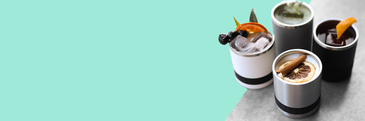 Barware cups with drinks and garnish on mint background.