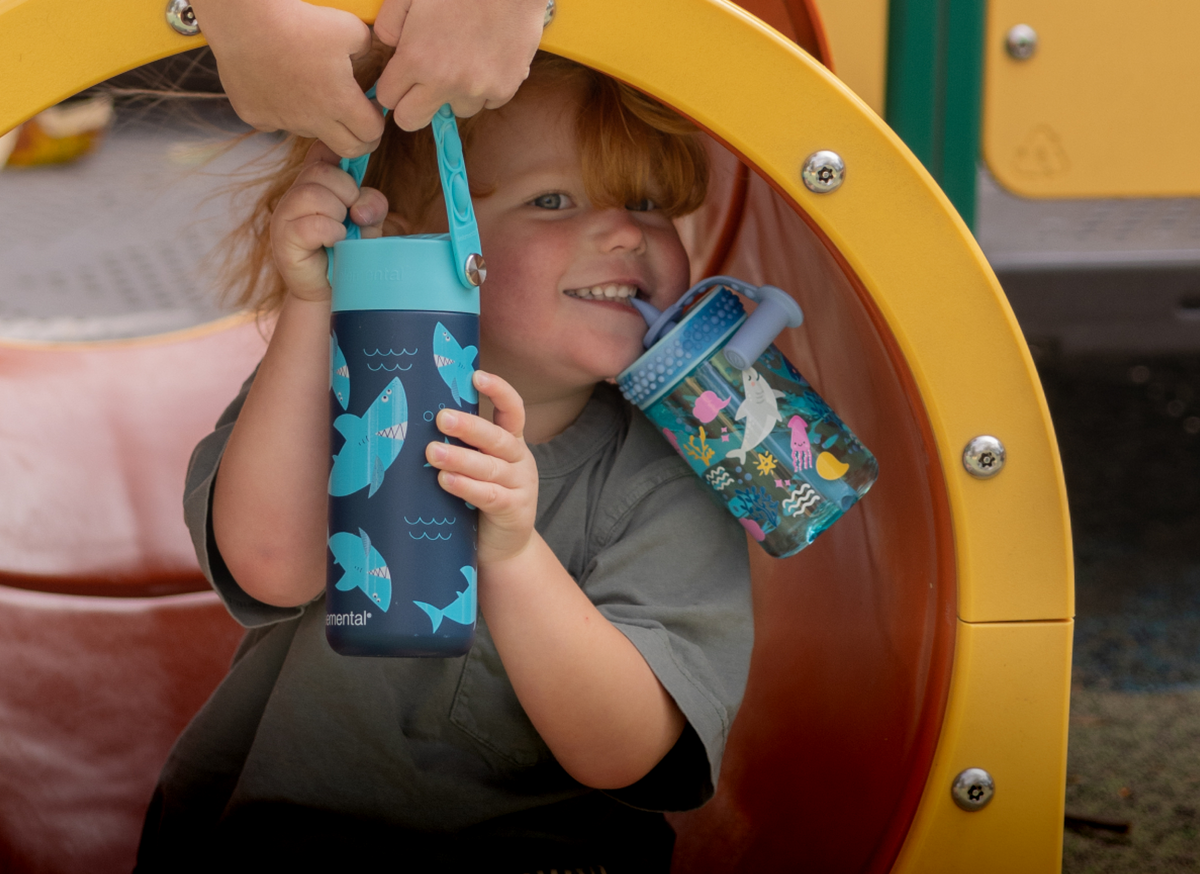 Kid sipping from a patterned Elemental bottle at the playground